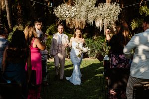 Wedding guests mingling outdoors during sunset at garden reception.
