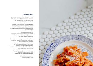 Close up of rigatoni pasta with tomato sauce on decorative blue and white plate.
