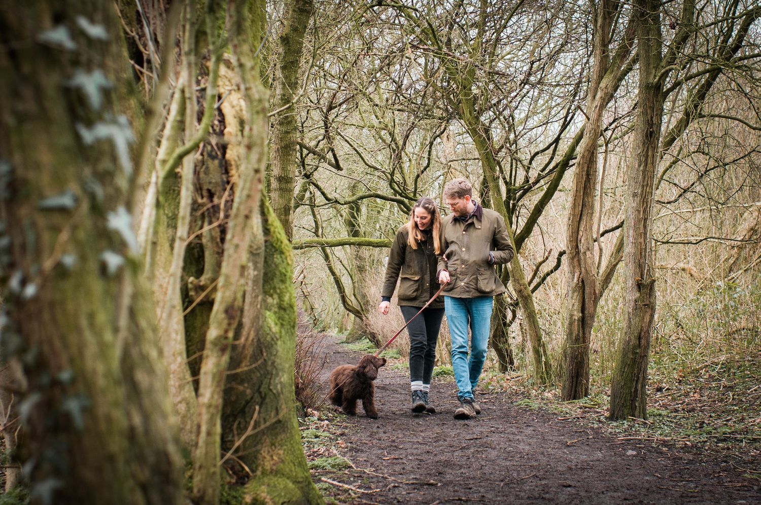 Couple walking through woodland in Carlisle with their dog.