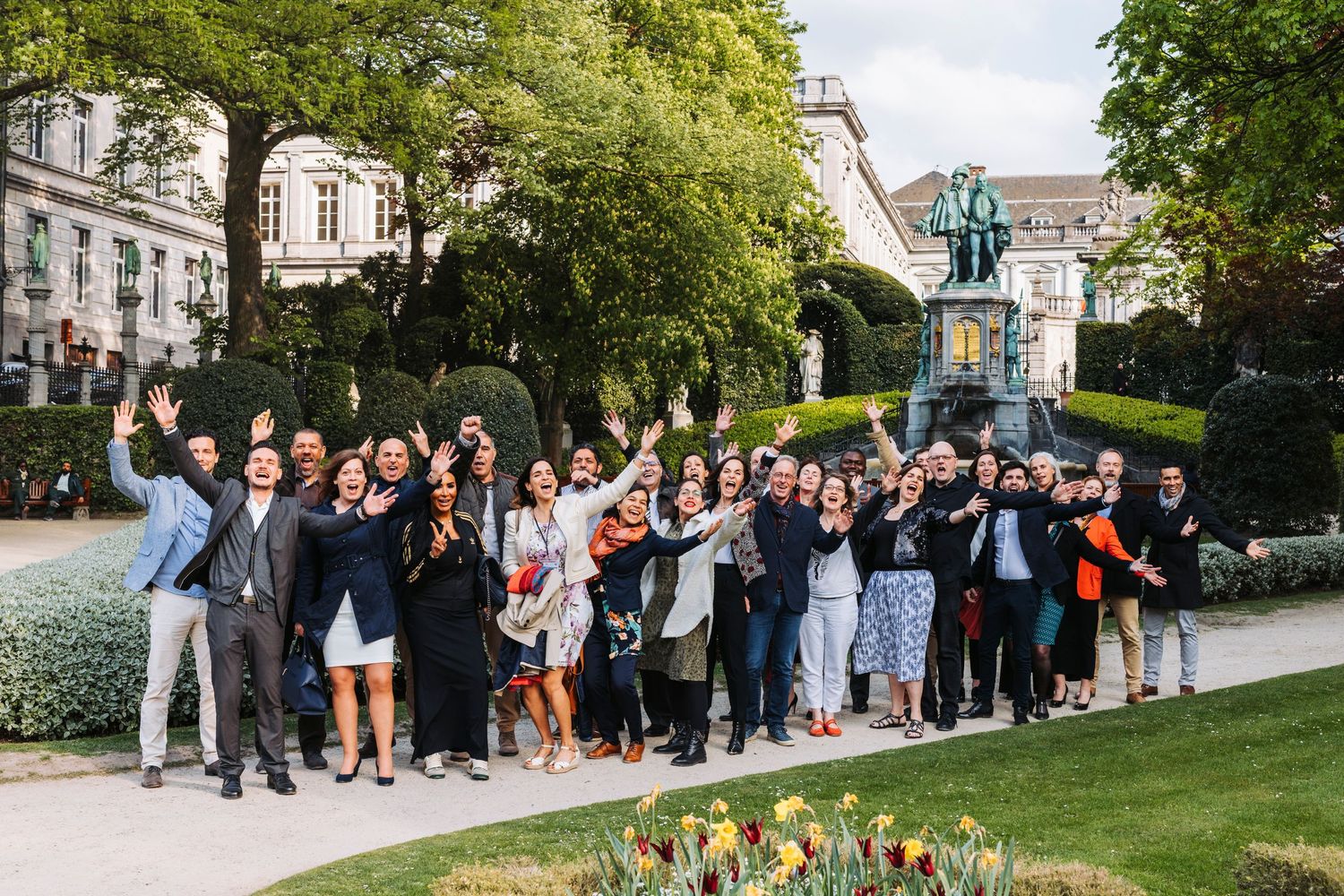 Large group posed together outdoors in front of classic architecture.