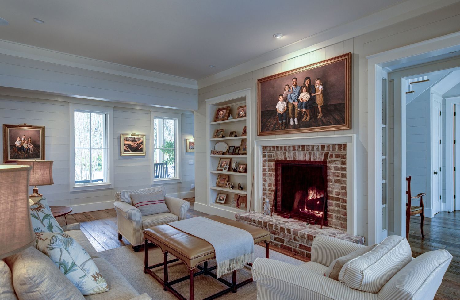 Living romm with white furniture, neutral colors, fireplace; various family wall portraits on walls and shelves; SC