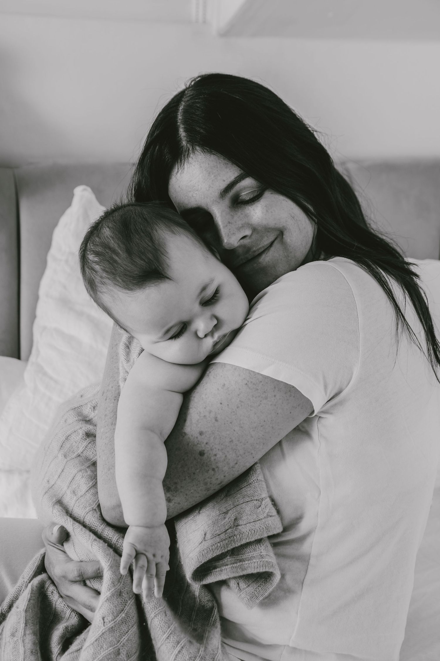Black and white photo capturing tender moment between mother and infant.