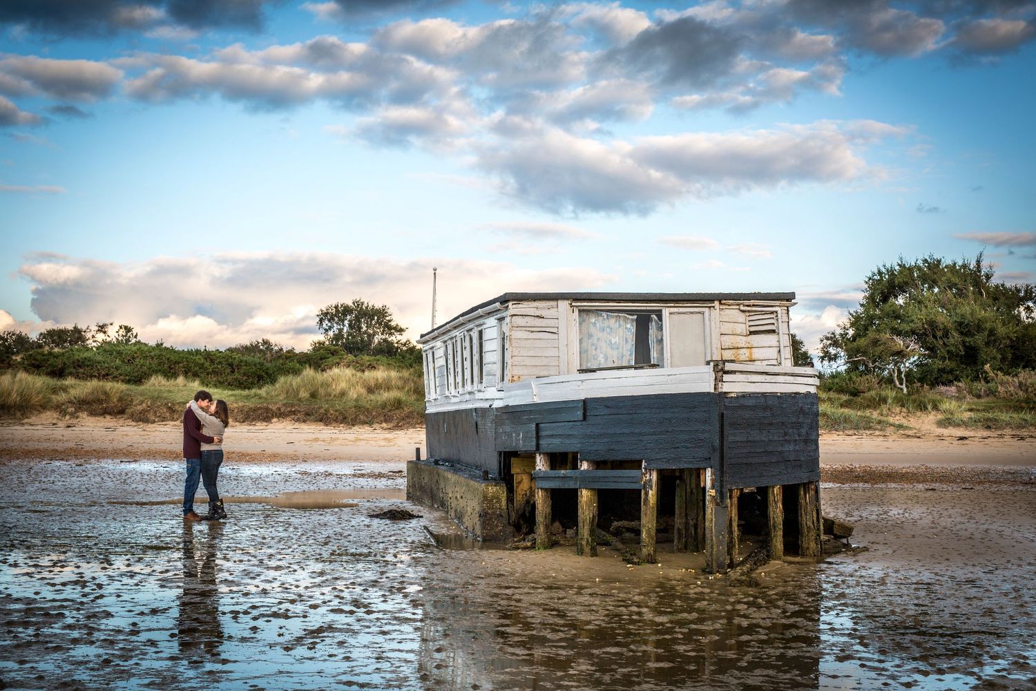 A scenic waterfront photo session with a building on stilts during high tide.