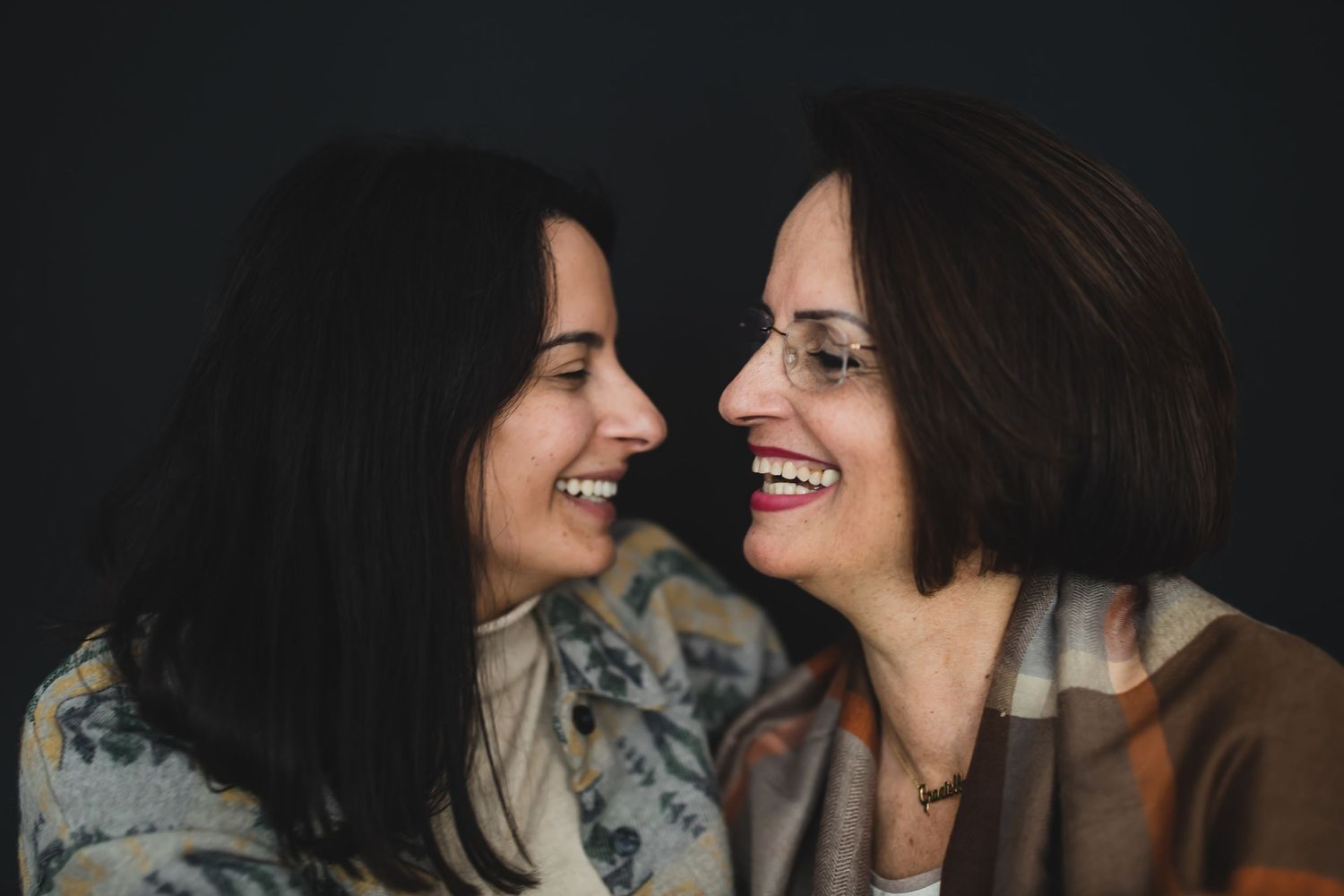 Two women sharing intimate laughter in a candid black and white close-up portrait.