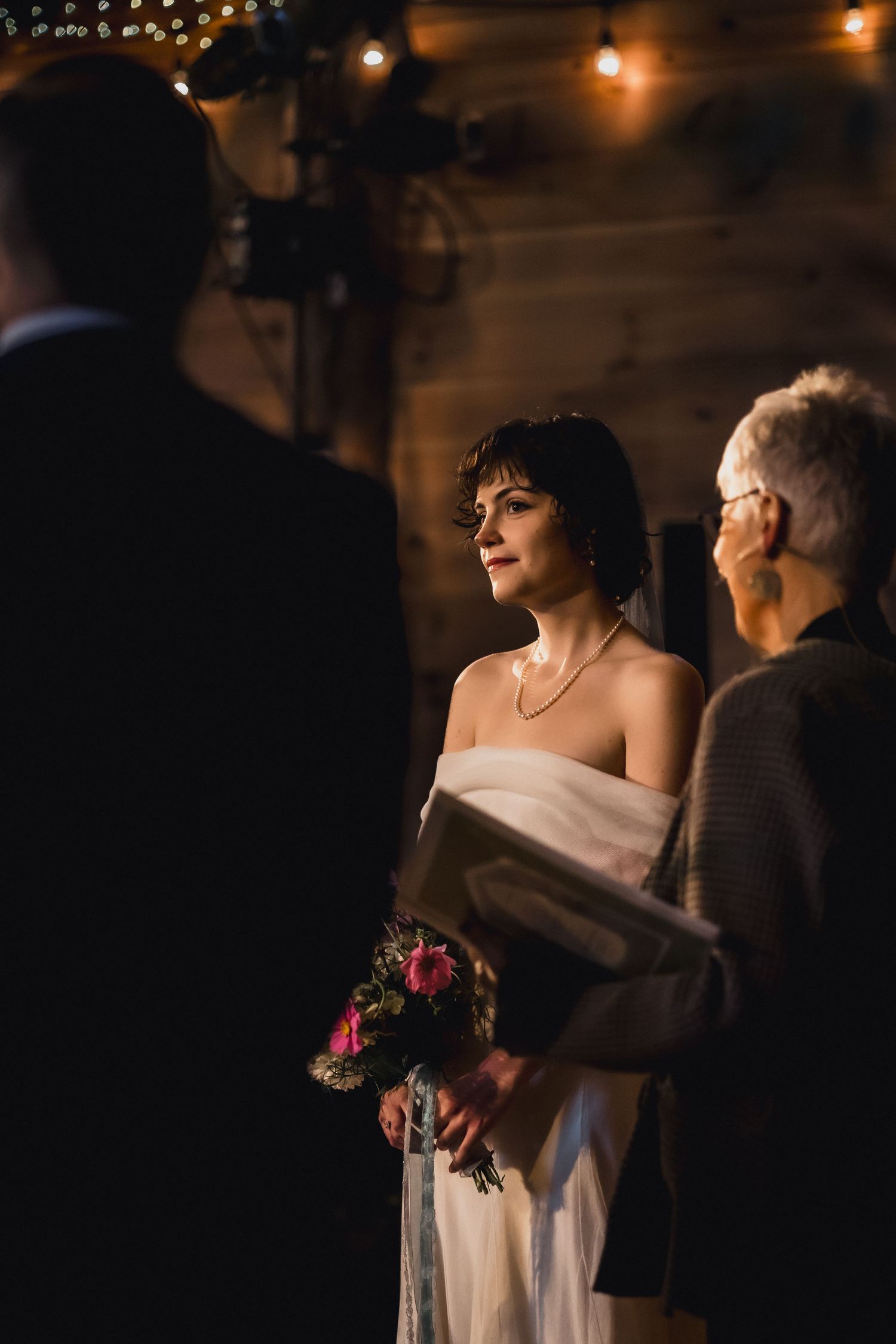 Wedding ceremony in progress with elegant decor and warm lighting in rustic indoor setting.