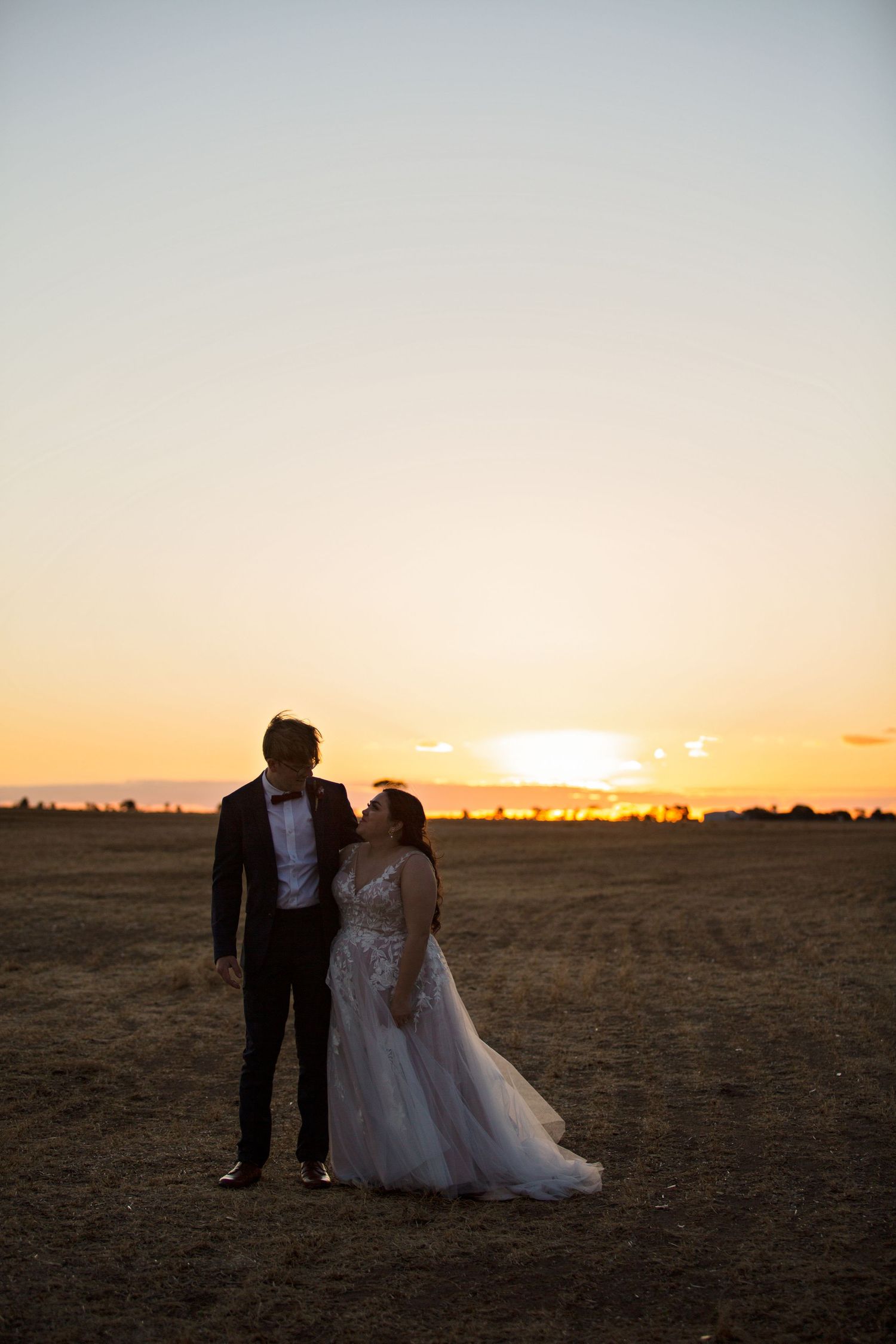 Bride and Groom standing in open field looking at each other at Redwing Farm