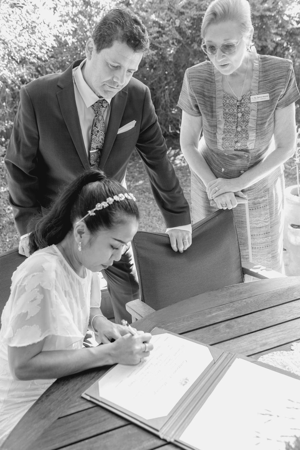mature asian bride and groom signing wedding register in backyard