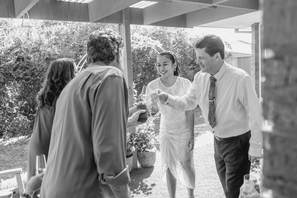 relaxed mature couple making champagne toast with witnesses after backyard elopement