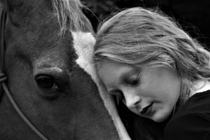 Intimate black and white portrait showing a tender moment between horse and human.