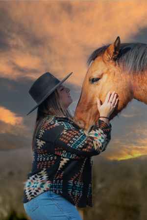 Horse and person sharing tender moment during golden sunset in western setting.