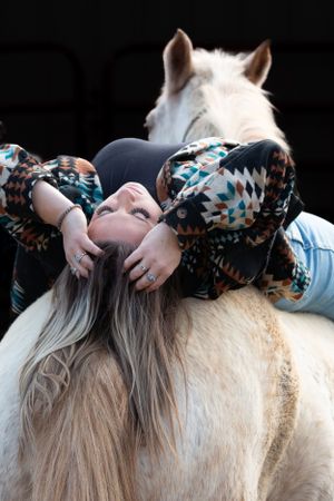White horse and rider in patterned sweater sharing peaceful moment together.