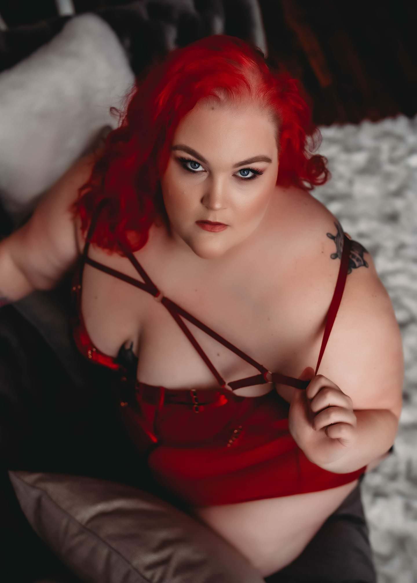 Dramatic portrait in red lingerie against dark background with striking makeup.