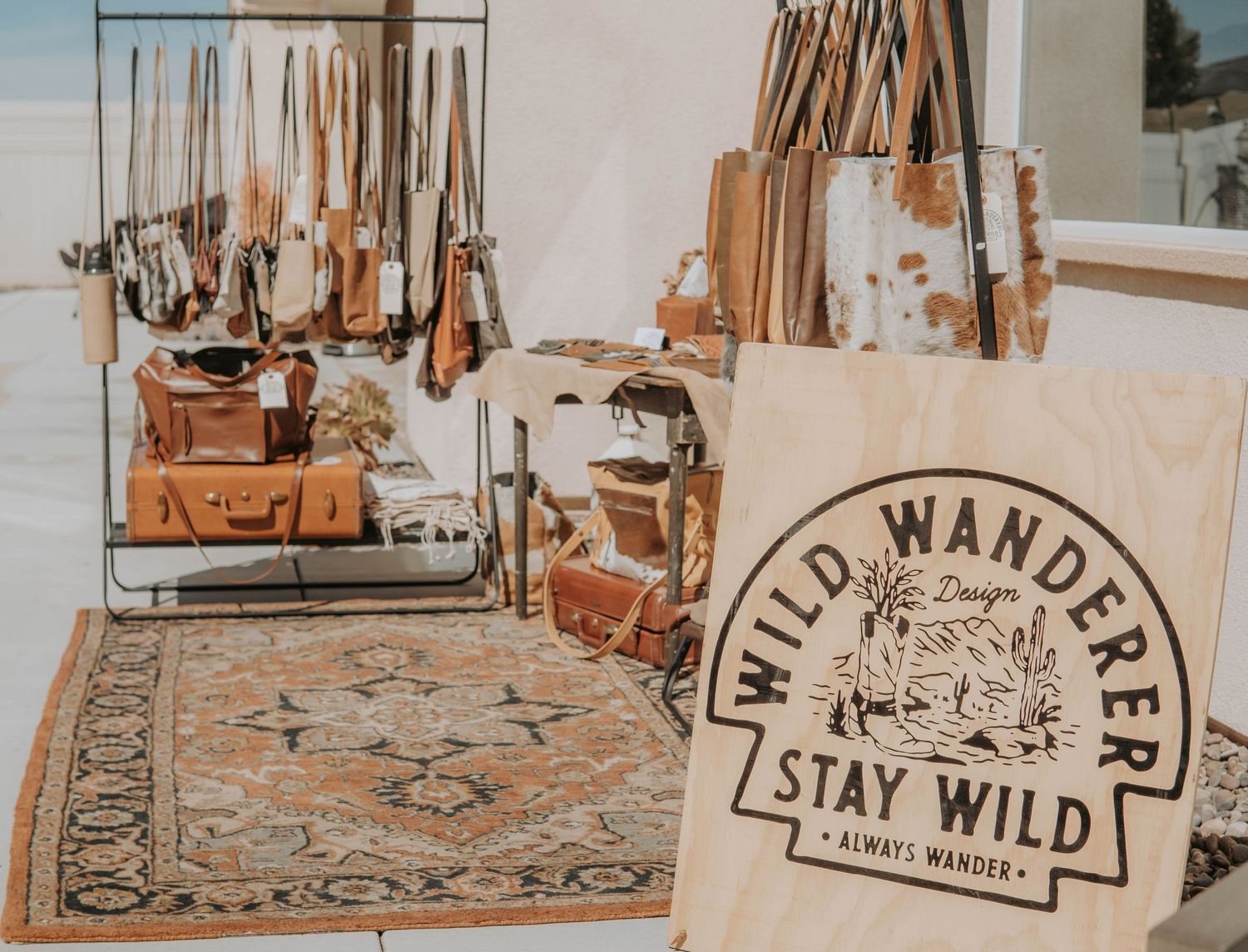 Boho style retail display with rugs and vintage decor against white wall.
