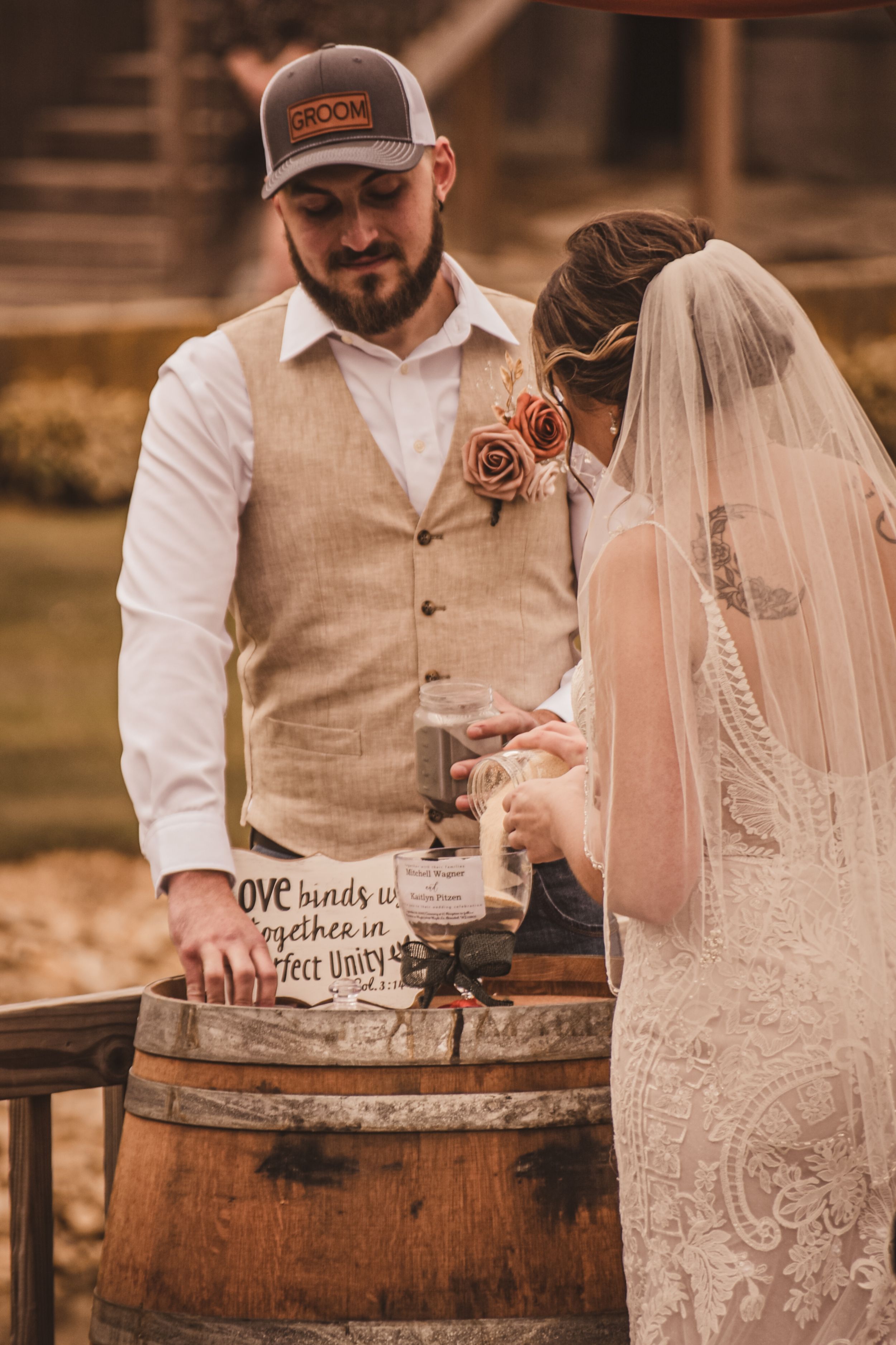 Couple performing unity ceremony with mason jars on rustic wooden barrel.