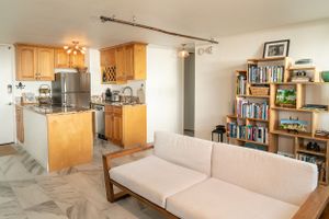 Open concept apartment with kitchen and living space featuring wooden cabinets and bookshelves. Realestate Photography