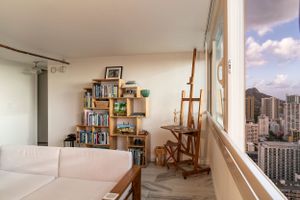 Bright studio space with art easel, bookshelves, and city views through large windows. Realestate Photography