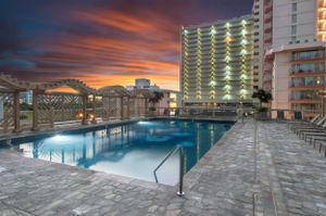 Resort swimming pool at sunset with illuminated high-rise buildings in the background. Realestate Photography