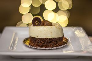 Elegant chocolate dessert with a decorative topper against blurred golden bokeh background. Food Photography