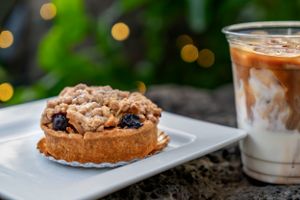Cookie sandwich with cream filling served alongside an iced latte on white plate. Food Photography