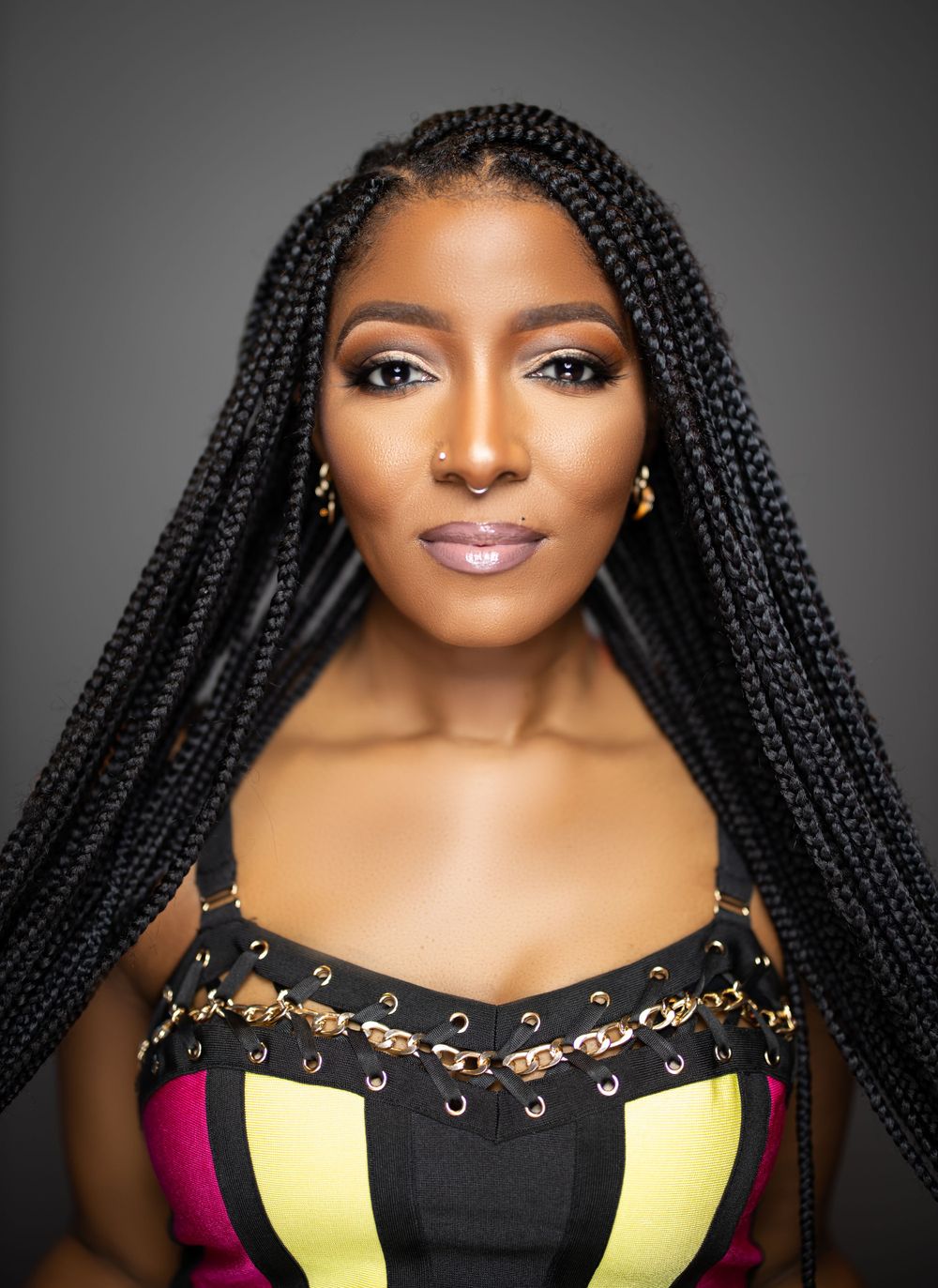 Elegant beauty shot showcasing long box braids and stylish black and multicolored top.