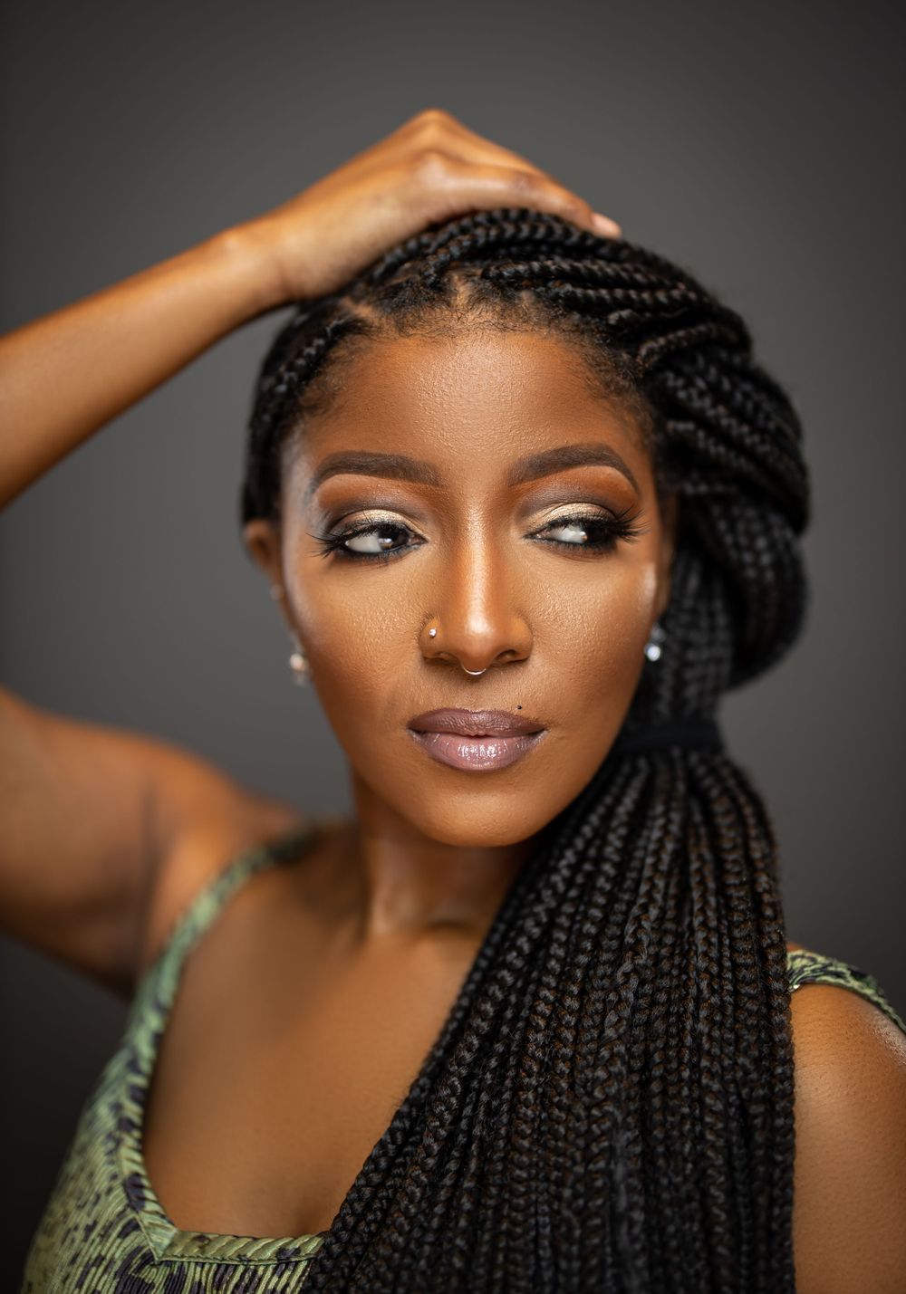 Beautiful portrait of model with long braided hairstyle and glamorous makeup against dark background.
