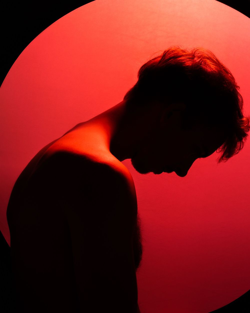 Dramatic silhouette of a person against a large red circle background with moody lighting.