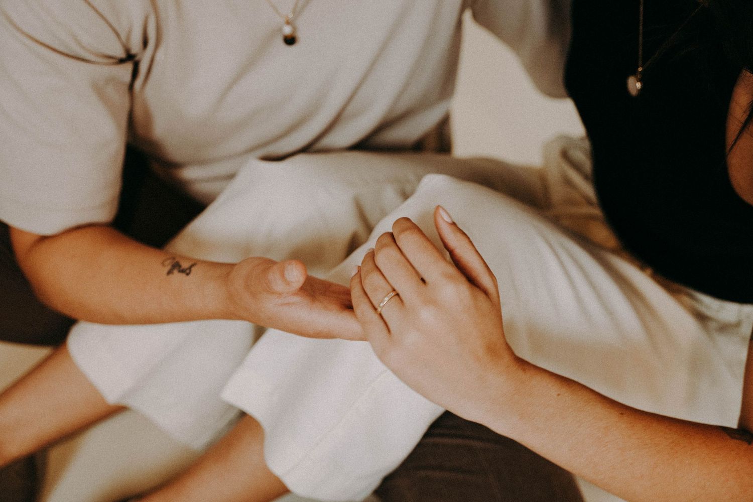 Couple holds hands in a studio engagement portrait to show off their wedding rings