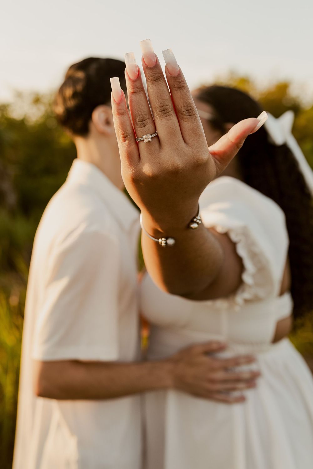 hand of a newly engaged bride covering her and her fiance's face with her ring