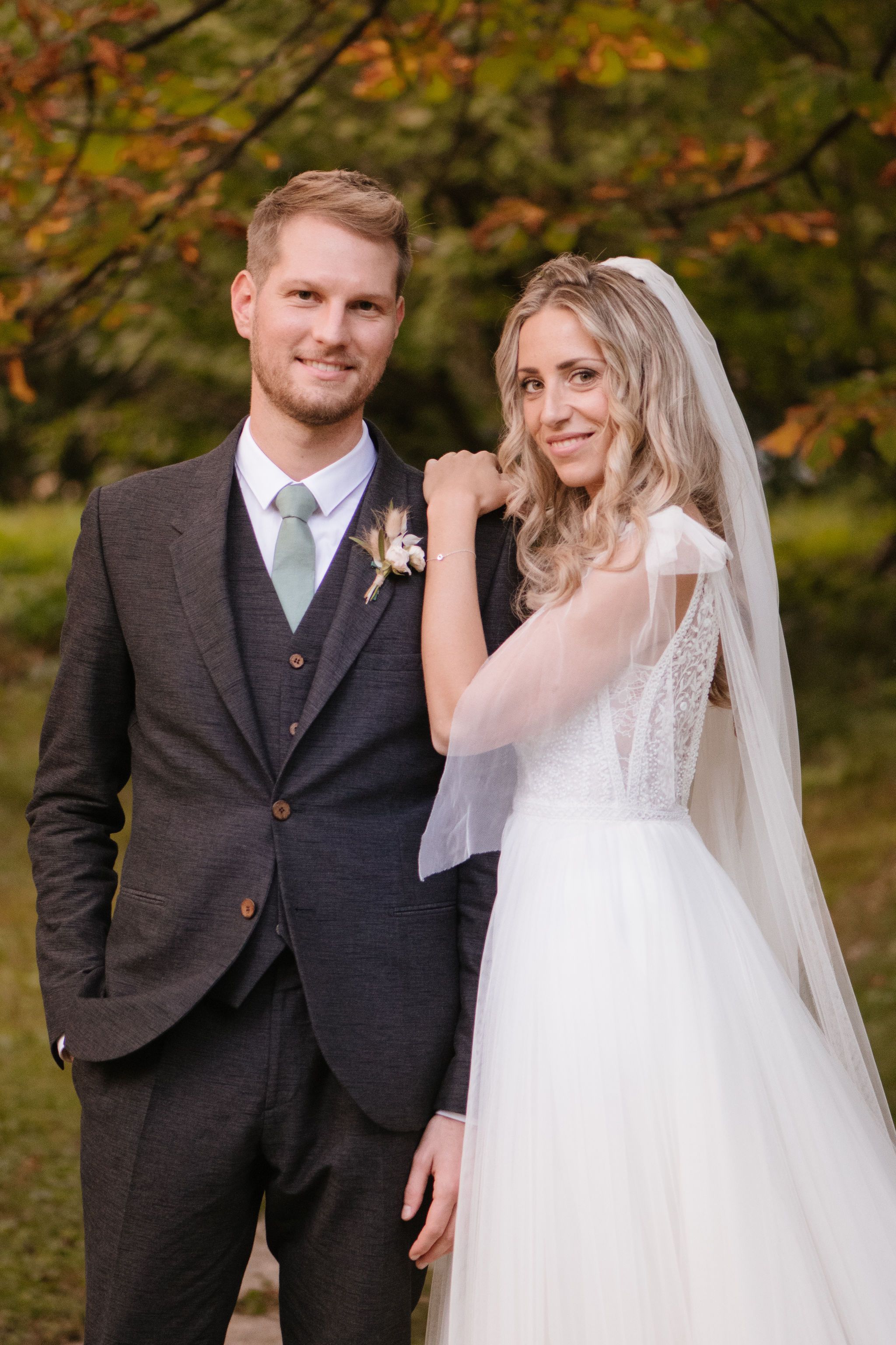 Wedding portrait in autumn setting with warm fall foliage in background.