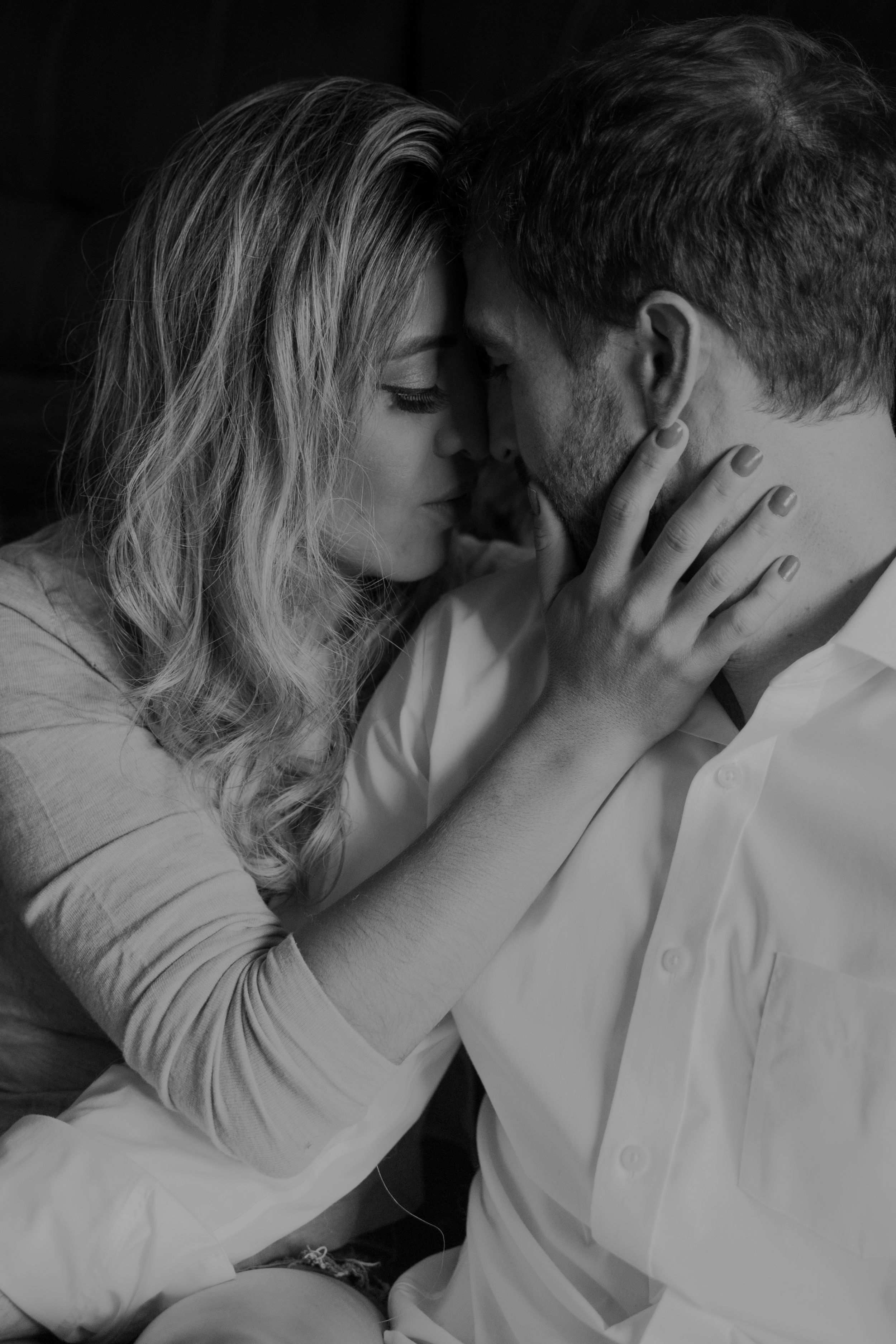 Intimate black and white portrait of a romantic couple sharing a tender moment.