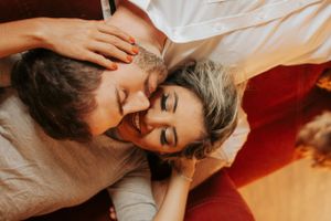 Romantic couple sharing intimate moments on couch in warm lighting.