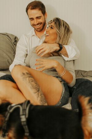 A playful couple laughing together while relaxing at home with their pets.