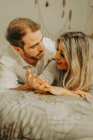 A couple sharing a tender moment while lying on bed together.