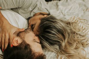 An intimate couple sharing a romantic kiss while lying down together.