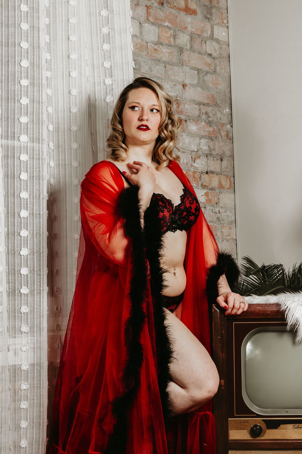Vintage-inspired boudoir scene with red robe and string lights.