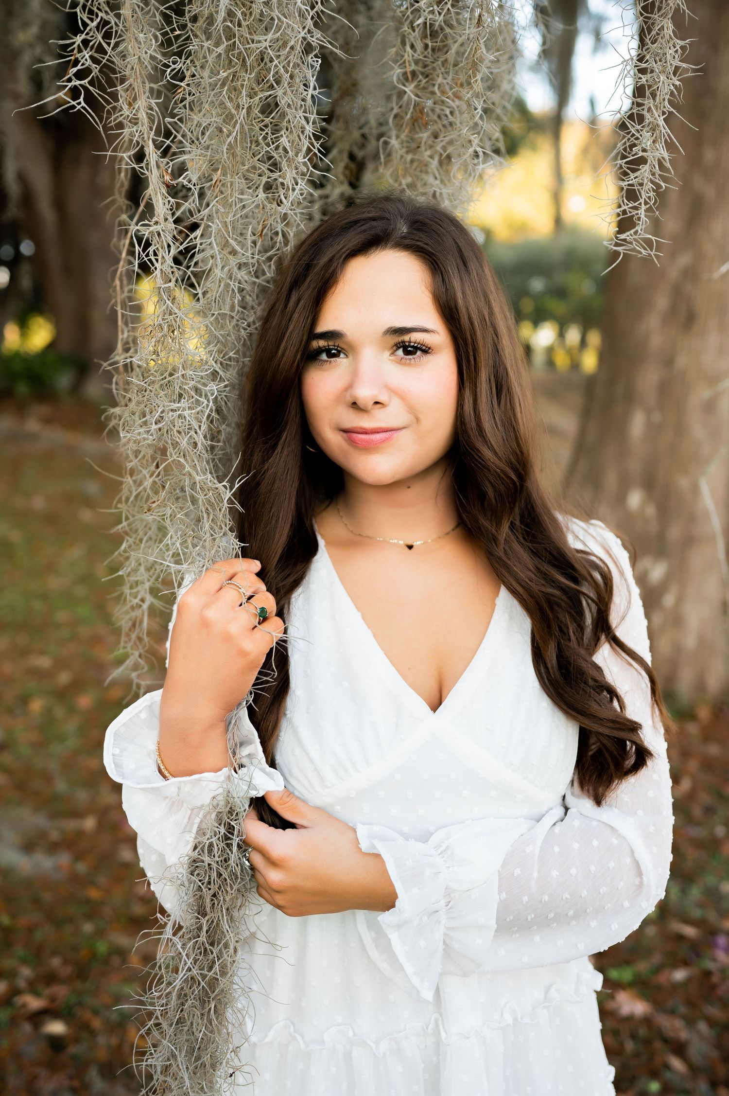 Portrait session featuring Spanish moss and natural lighting in a white lace dress outdoors.