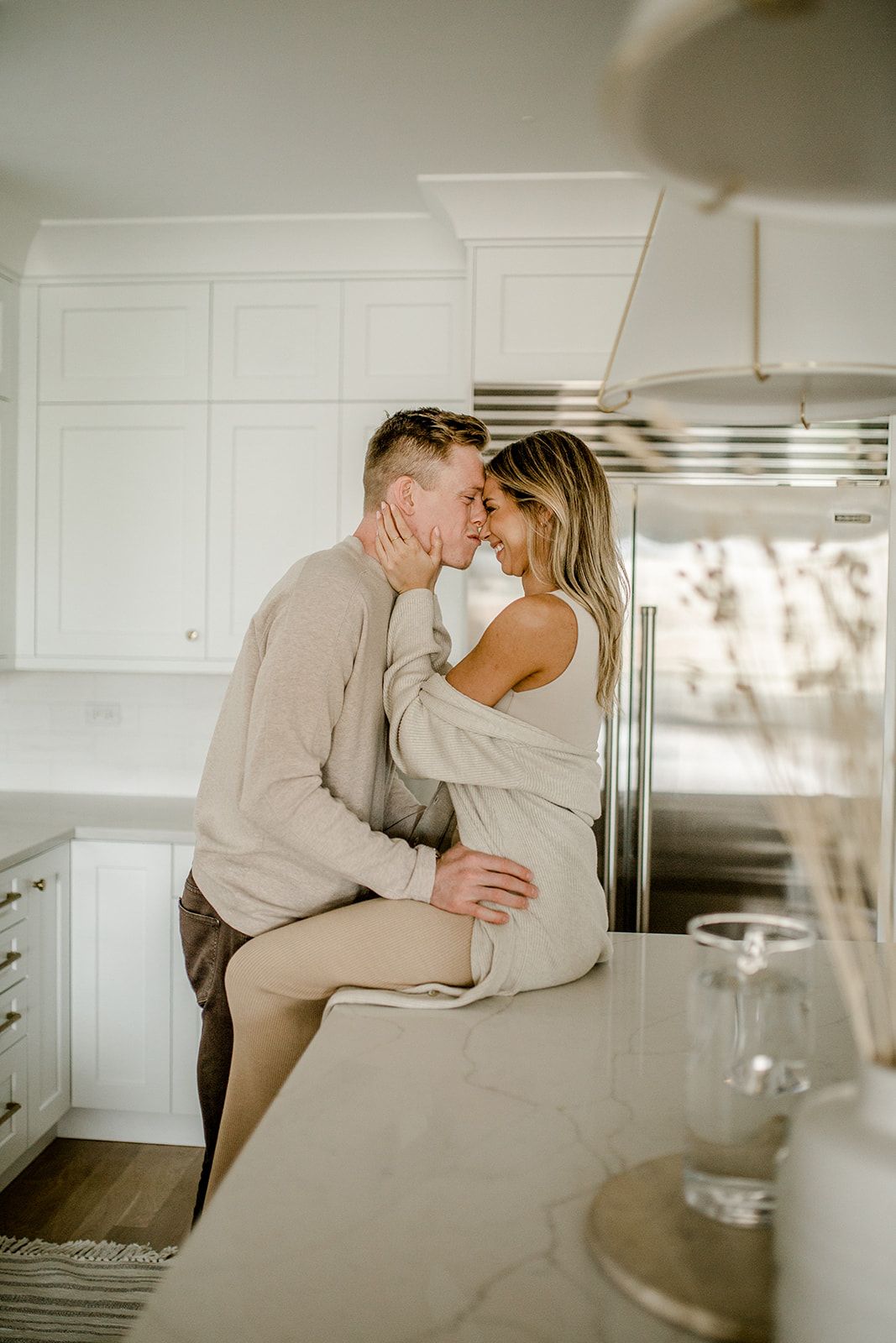A romantic moment shared between a couple in a modern white kitchen.