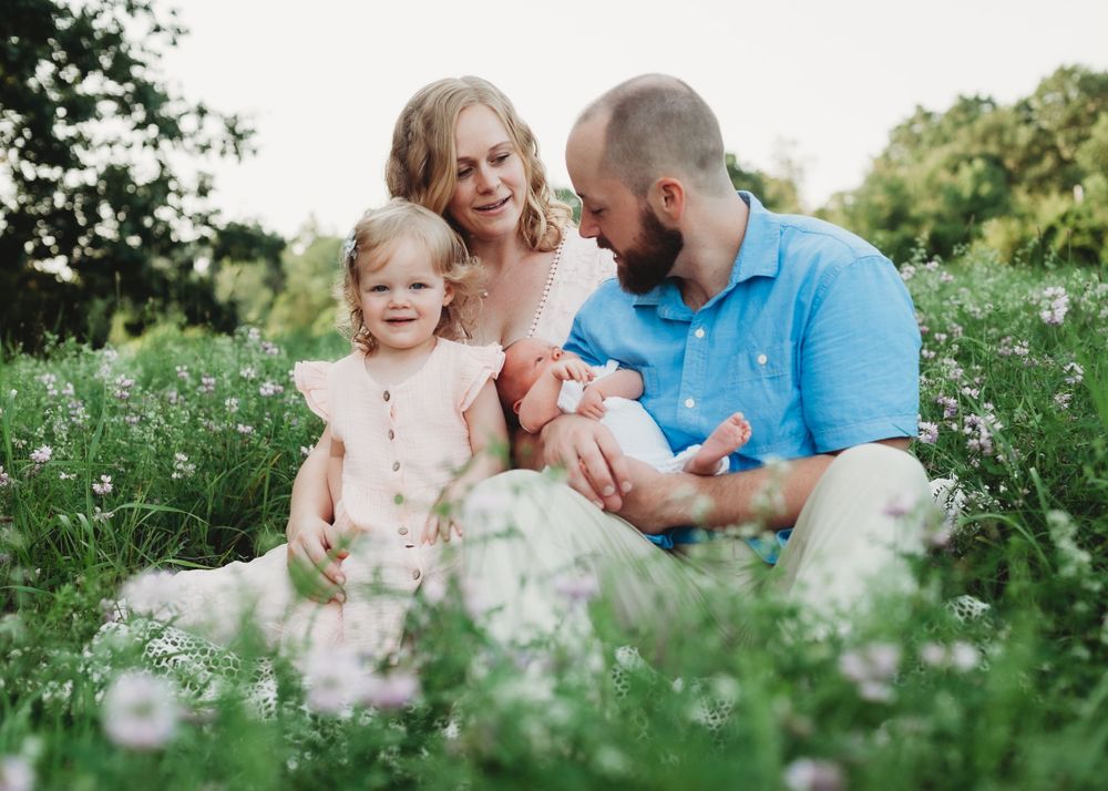 family of four poses with newborn baby in grassy field at Callahan State Park in Framingham, MA