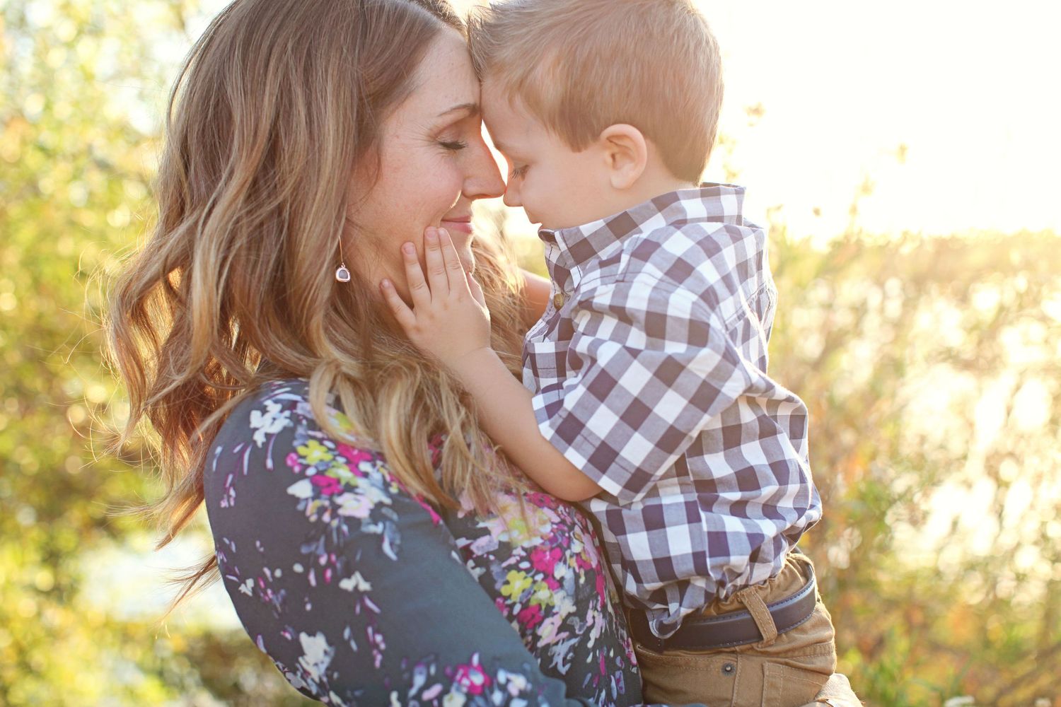 Tender moment captured between two people in a sunlit outdoor setting.