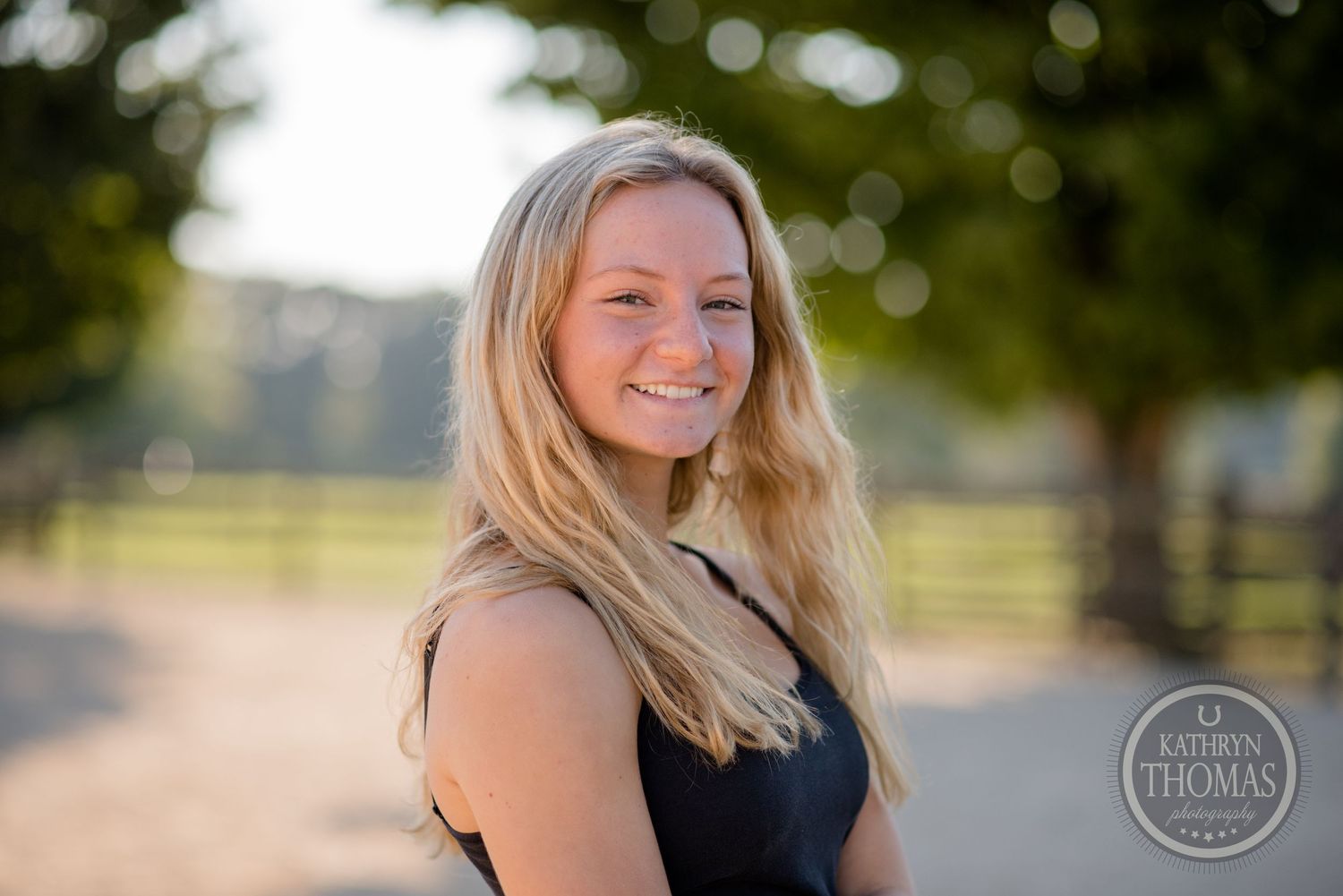 Portrait photo taken outdoors with natural bokeh lighting and fence backdrop.