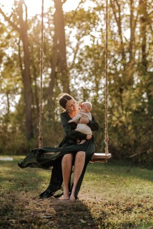woman and baby on a wooden swing in the sunshine