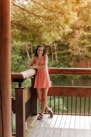 a teen girl standing up against a deck fence