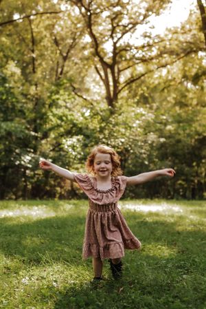 a little girl running towards the camera, arms spread wide