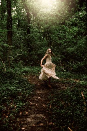 a girl twirling her flowy dress in the woods