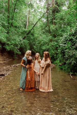 2 girls and 2 women huddle closely in a creek