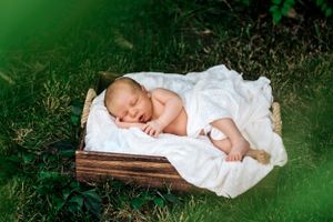 newborn baby wrapped in white, outside
