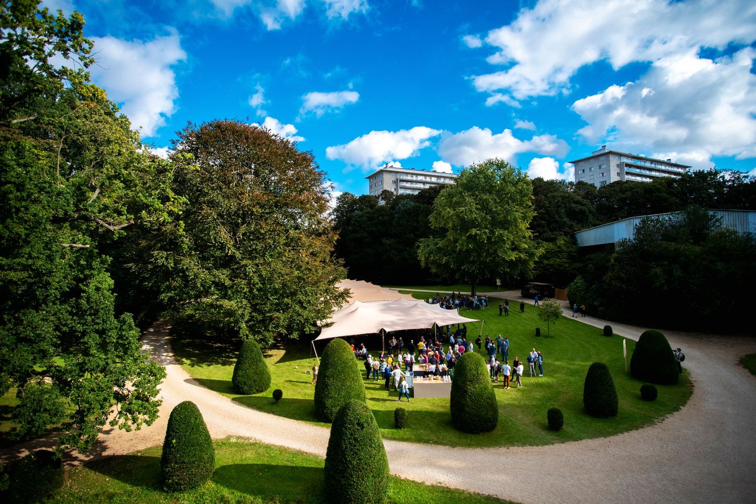 Aerial view of an outdoor wedding venue with manicured gardens under blue skies.