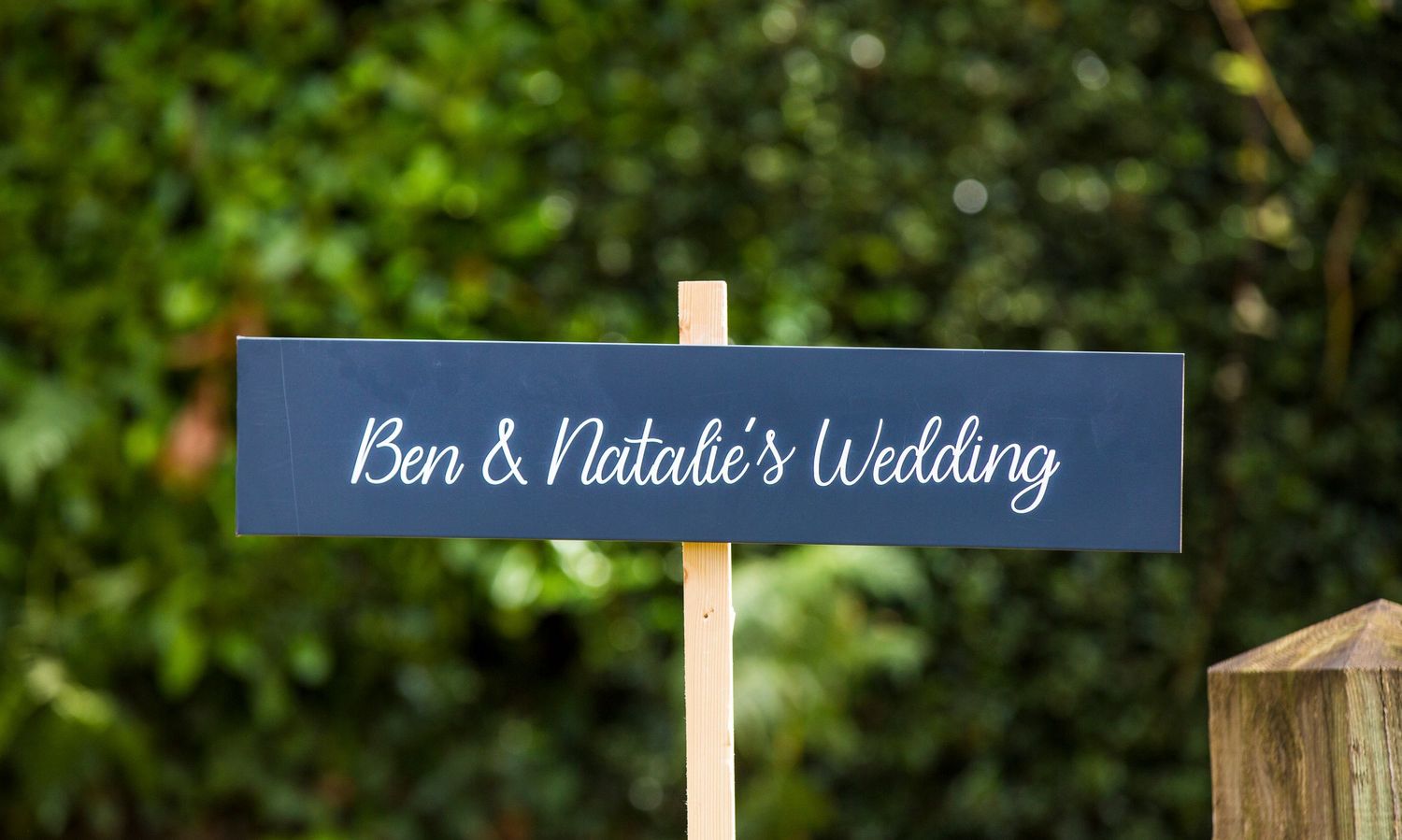 Wooden directional signs mark the path at an outdoor wedding venue.