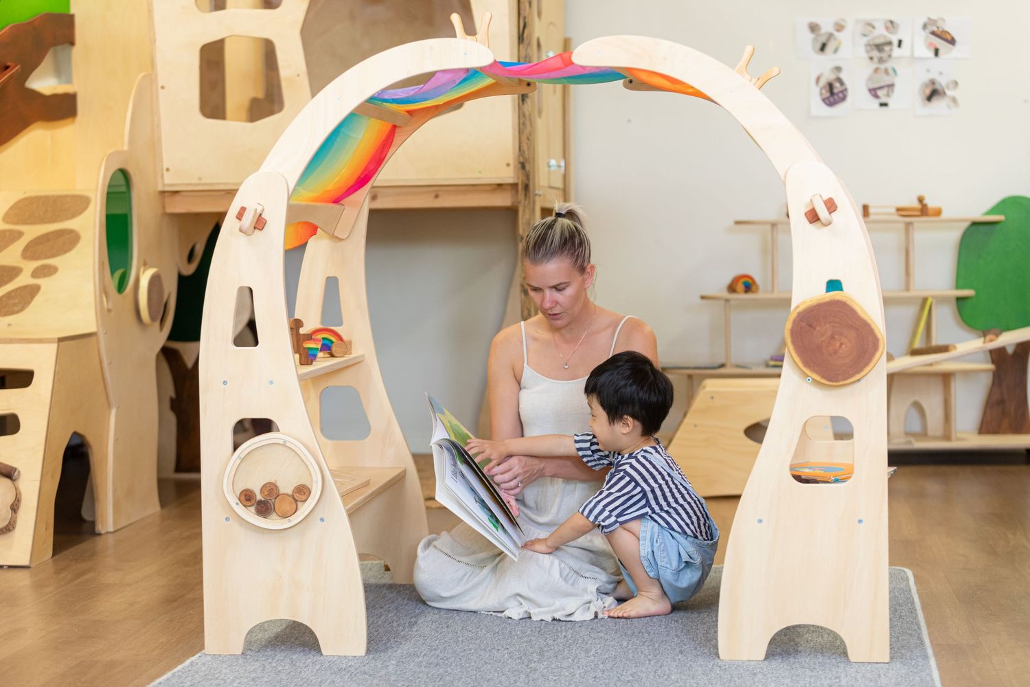 Children reading together under a decorative wooden play arch in a playroom.