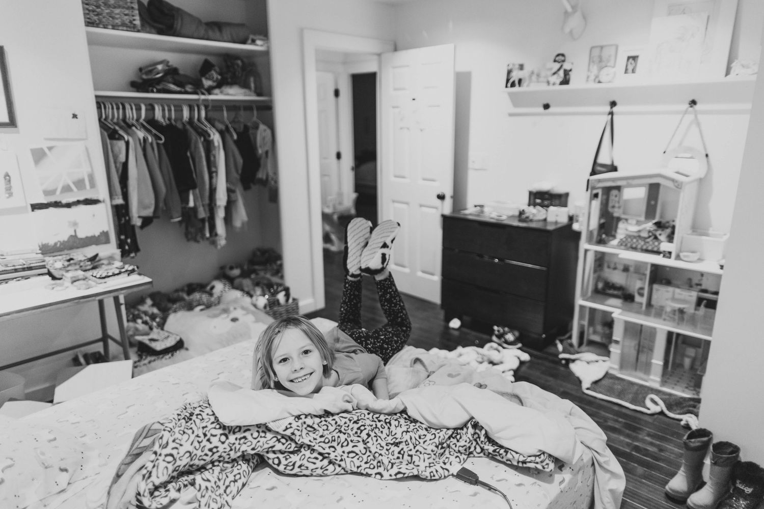 Black and white panoramic view of a disorganized bedroom space.